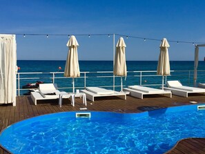 A poolside area with lounge chairs and umbrellas, overlooking the sea. - Bono Beach Hotel (Odesa)