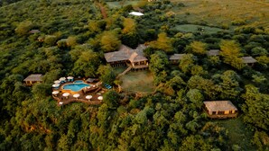 Luchtbeeld van een resort met meerdere gebouwen, een zwembad en een verzorgde tuin.