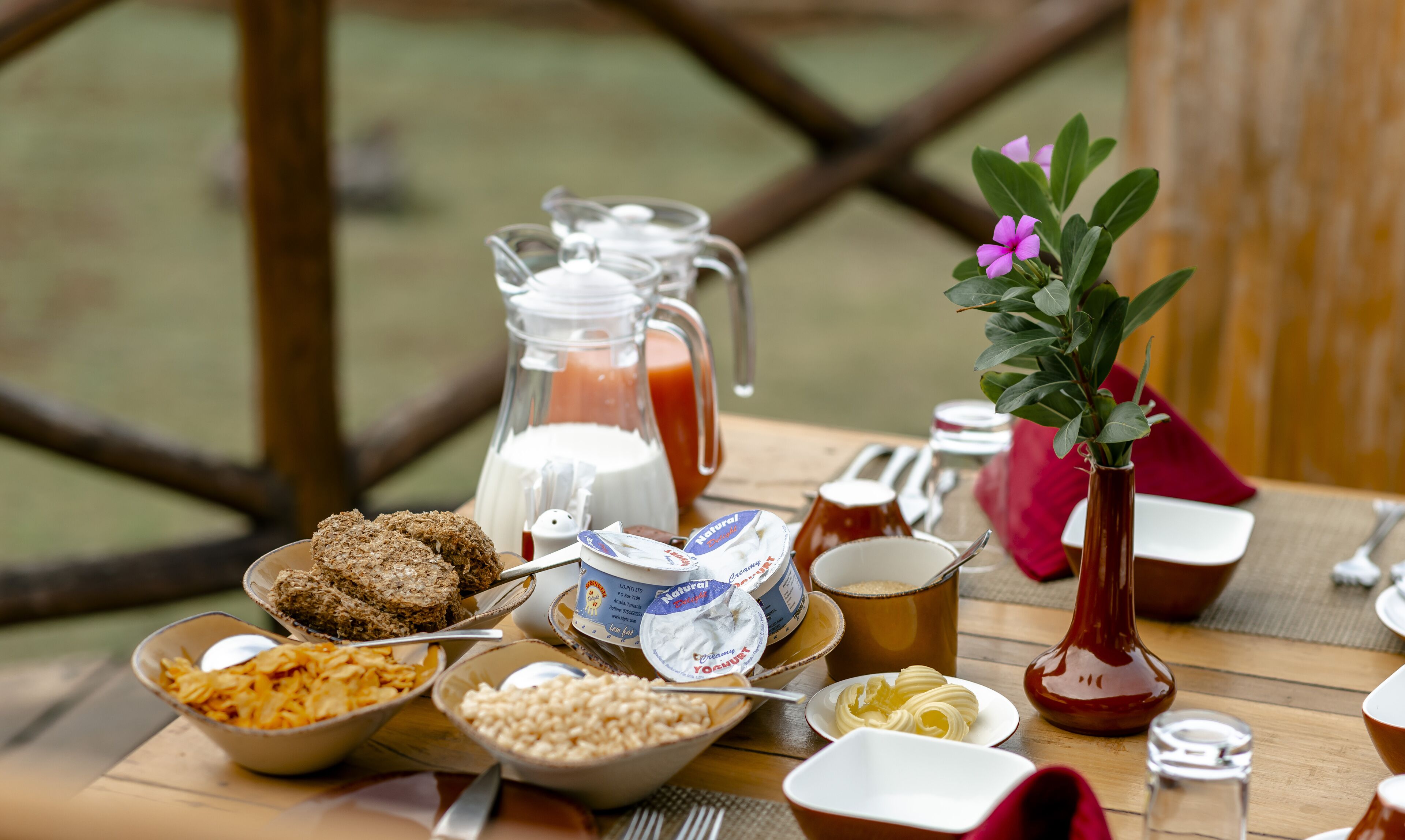A breakfast table with various food items, including cereal, butter, and a pitcher of juice.