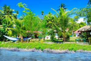 A tropical beach scene with a boat, palm trees, and a thatched-roof hut. - Bluewhale Lagoon Resort (Ahangama)