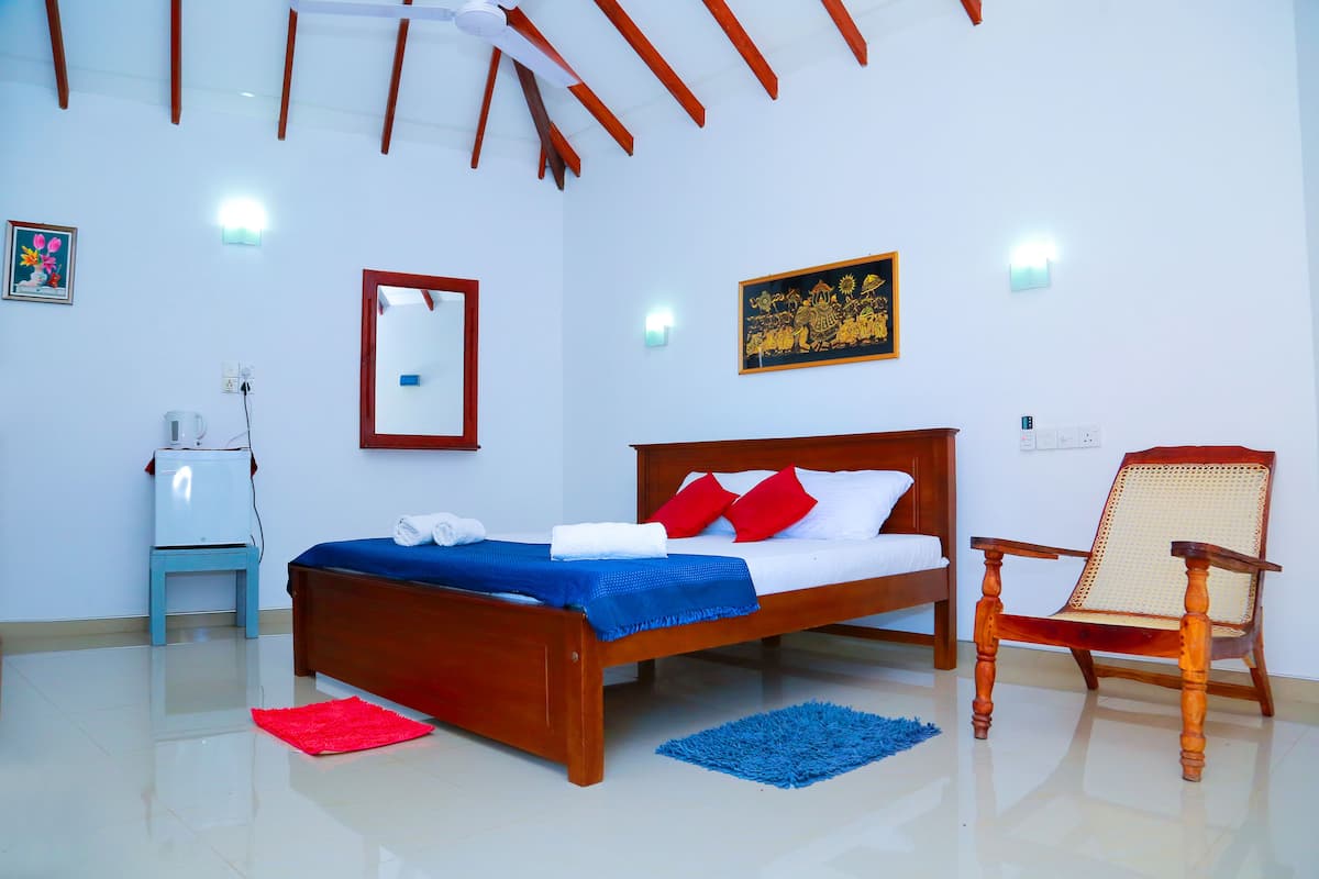 A bedroom with a wooden bed, a chair, a small table, and a mirror.