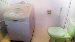 Un bagno compatto con il water bianco, un piccolo cestino e una lavatrice.