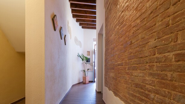 A hallway with a brick wall on one side and a white wall on the other, leading to a door at the end. - B&B Il Borgo (Cagliari)