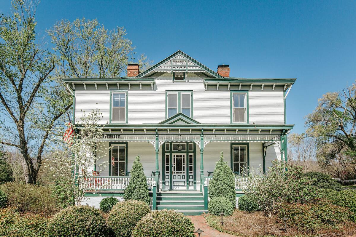 A two-story house with a front porch, green trim, and a central entrance.