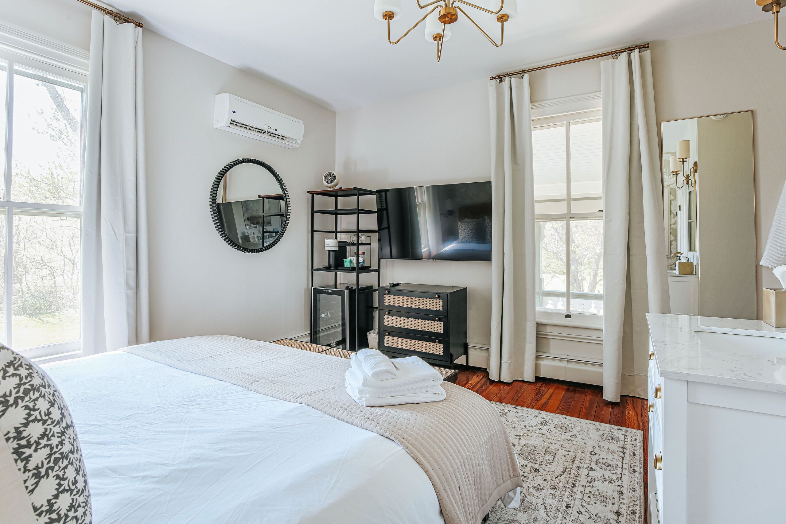 Un dormitori amb un llit, televisió, un calaix i un mirall.