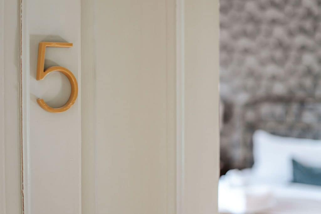 Une porte avec une plaque en bois portant le chiffre « 5 ».