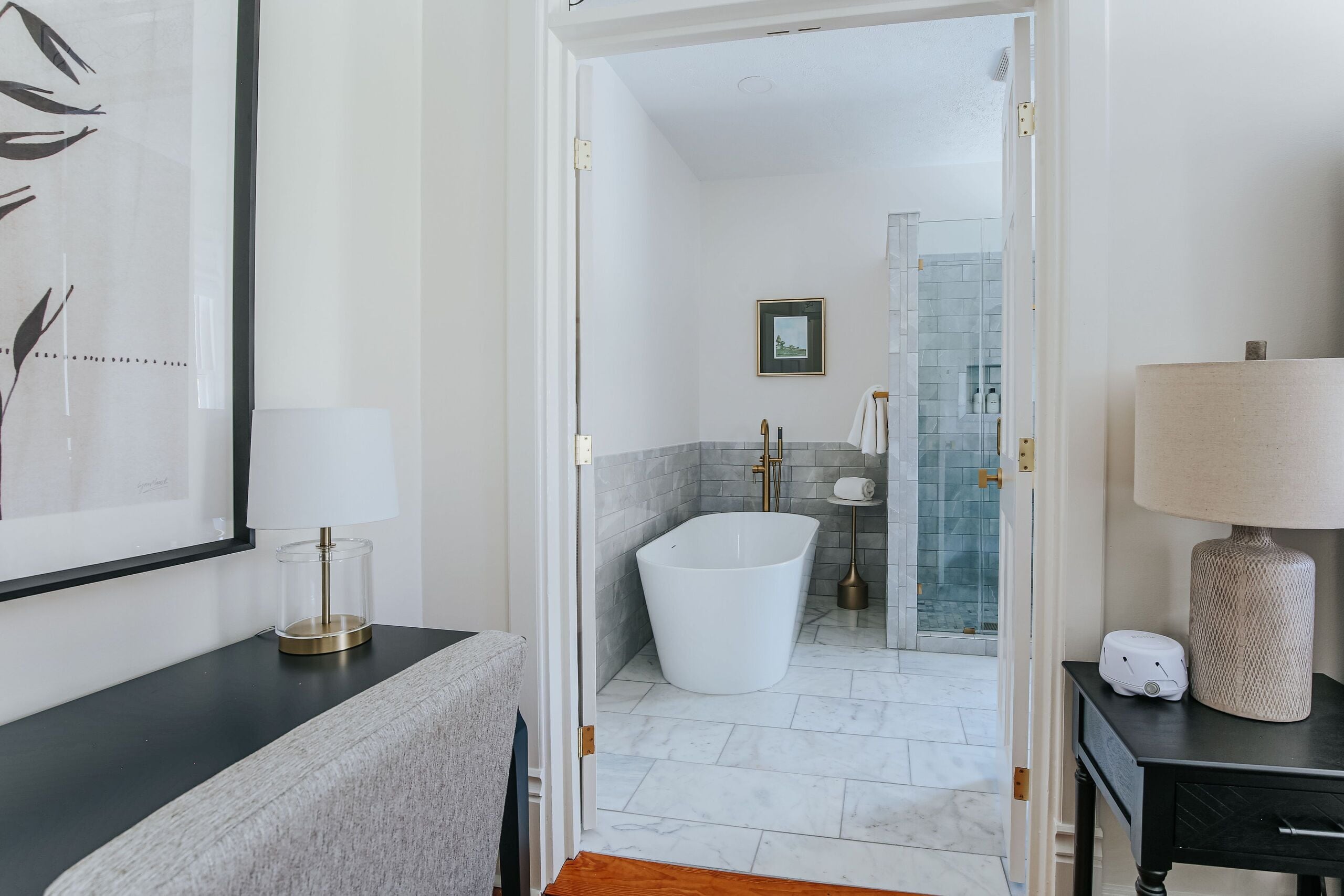 A modern bathroom with a freestanding bathtub, a glass shower enclosure, and a framed picture on the wall.