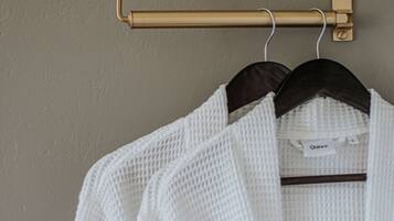 A white knitted sweater hanging on a gold-colored hanger against a textured wall.