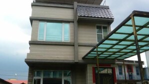A modern two-story building with a flat roof, large windows, and a covered outdoor area with a glass roof. - Wish Enjoy Happy Homestay (Ligang)