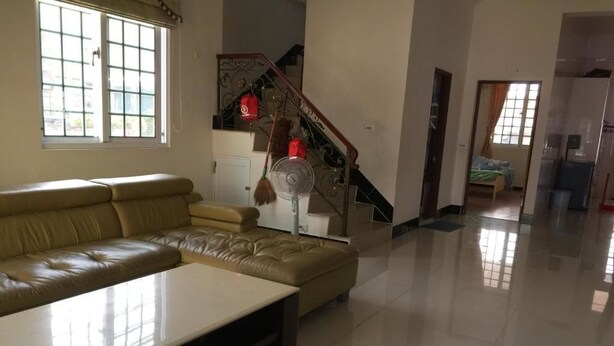 A spacious living room with a leather sofa, a coffee table, and a standing fan. - Wish Enjoy Happy Homestay (Ligang)