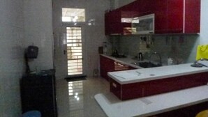 A compact kitchen with a white countertop, red cabinets, and a microwave. - Wish Enjoy Happy Homestay (Ligang)