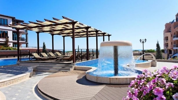 Uma área de piscina no terraço com hidromassagem, espreguiçadeiras e um pérgola.