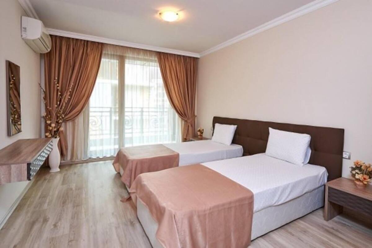 A hotel room with two beds, a desk, and a nightstand.
