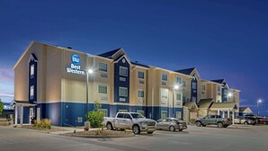 Ein Best Western Hotel mit einem mehrstöckigen Gebäude, einem Parkplatz mit mehreren Fahrzeugen und einem gut beleuchteten Eingang.