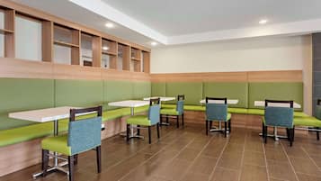 A restaurant with green cushioned booths, wooden tables, and blue chairs.