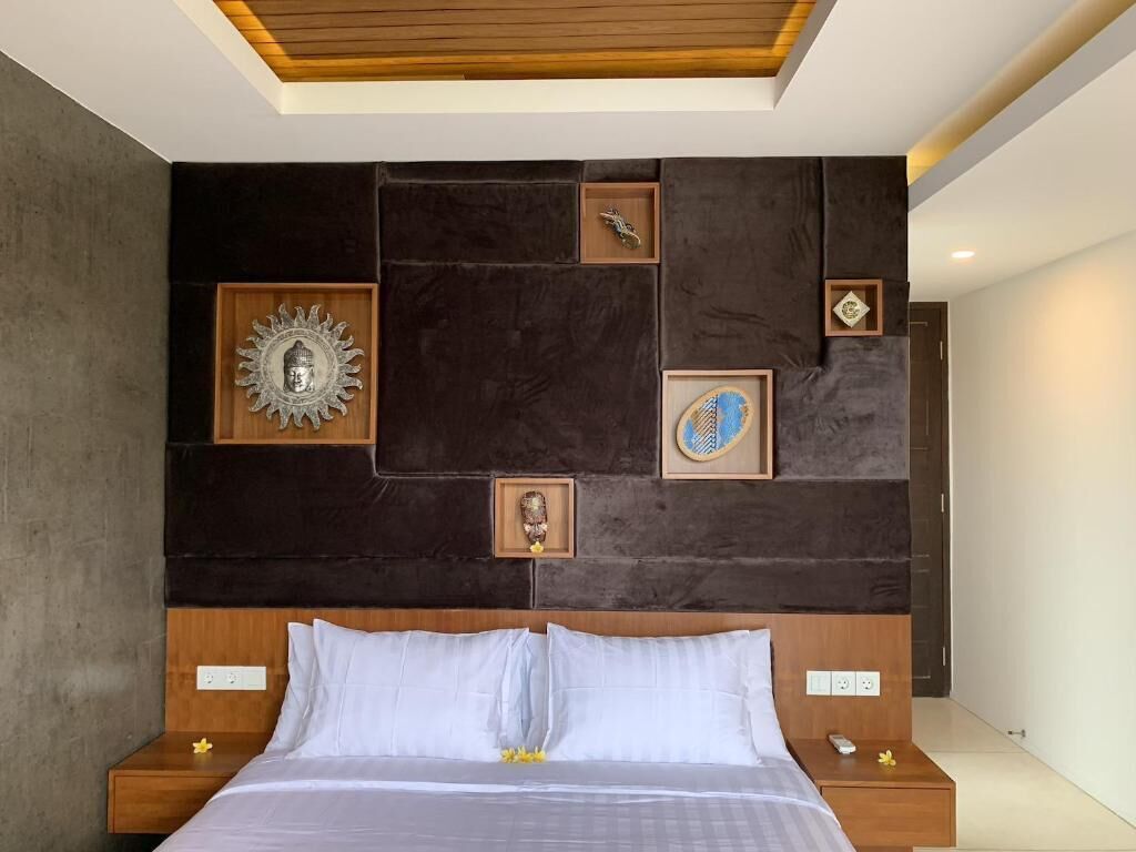 A modern hotel room with a large bed, dark wall paneling, and framed artwork.