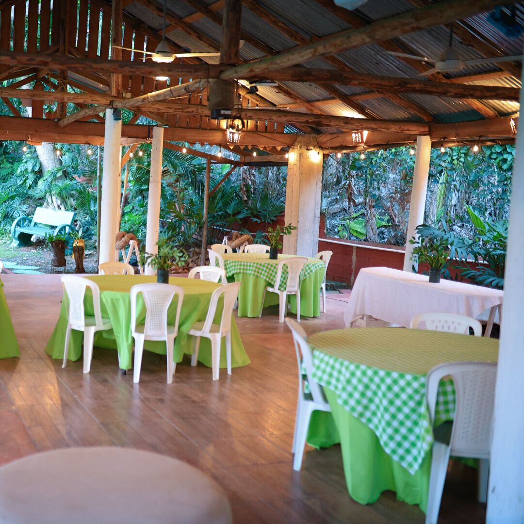 Un restaurant a l'aire lliure amb taules i caires, envoltat de vegetació exuberància.