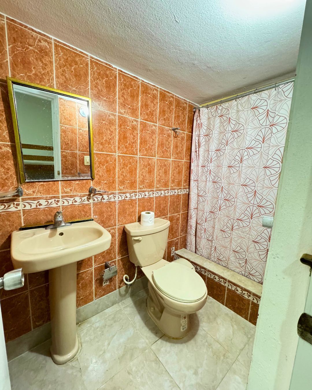 Un baño con lavamanos, inodoro y espejo.