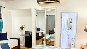 A hotel room with a large bed, a desk, a chair, a potted plant, and a bathroom visible through an open door. - Hotel Santo Cerro Natural Park  (La Vega)