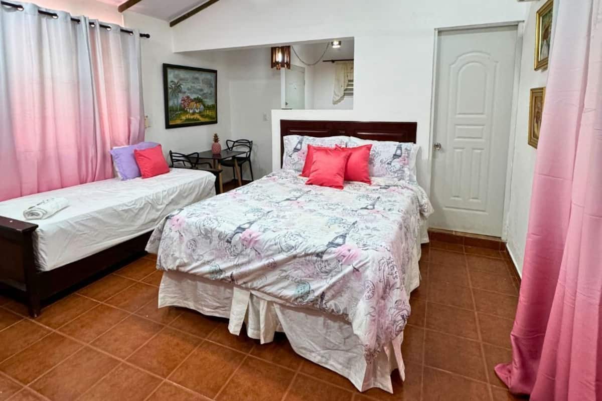 Ein Schlafzimmer mit zwei Betten, einem Deckenventilator und einem Essbereich mit Tisch und Stühlen.