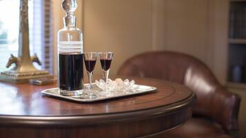 A tray with a decanter and two glasses of red wine on a wooden table.