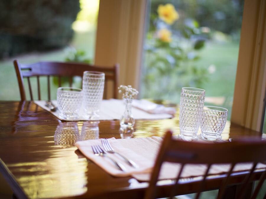 A dining table set with clear glassware and a vase of white flowers.