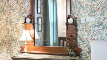 A wooden dresser with a mirror above it, a lamp on the dresser, and a chair to the right.