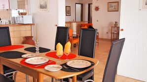 Un comedor con una mesa de madera dispuesta para dos personas, con individuales rojos, sillas negras y un candelabro decorativo.