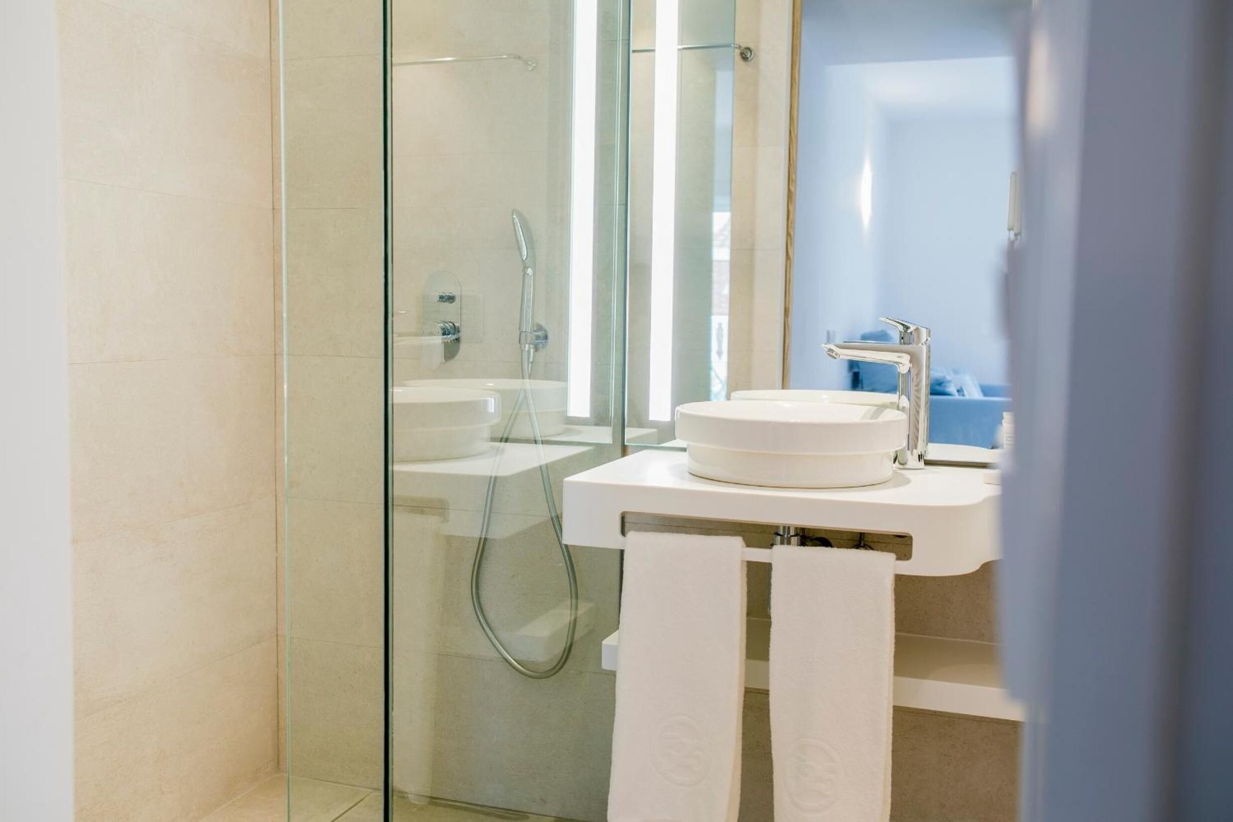 Un baño moderno con cabina de ducha de vidrio, un lavabo blanco y un espejo.