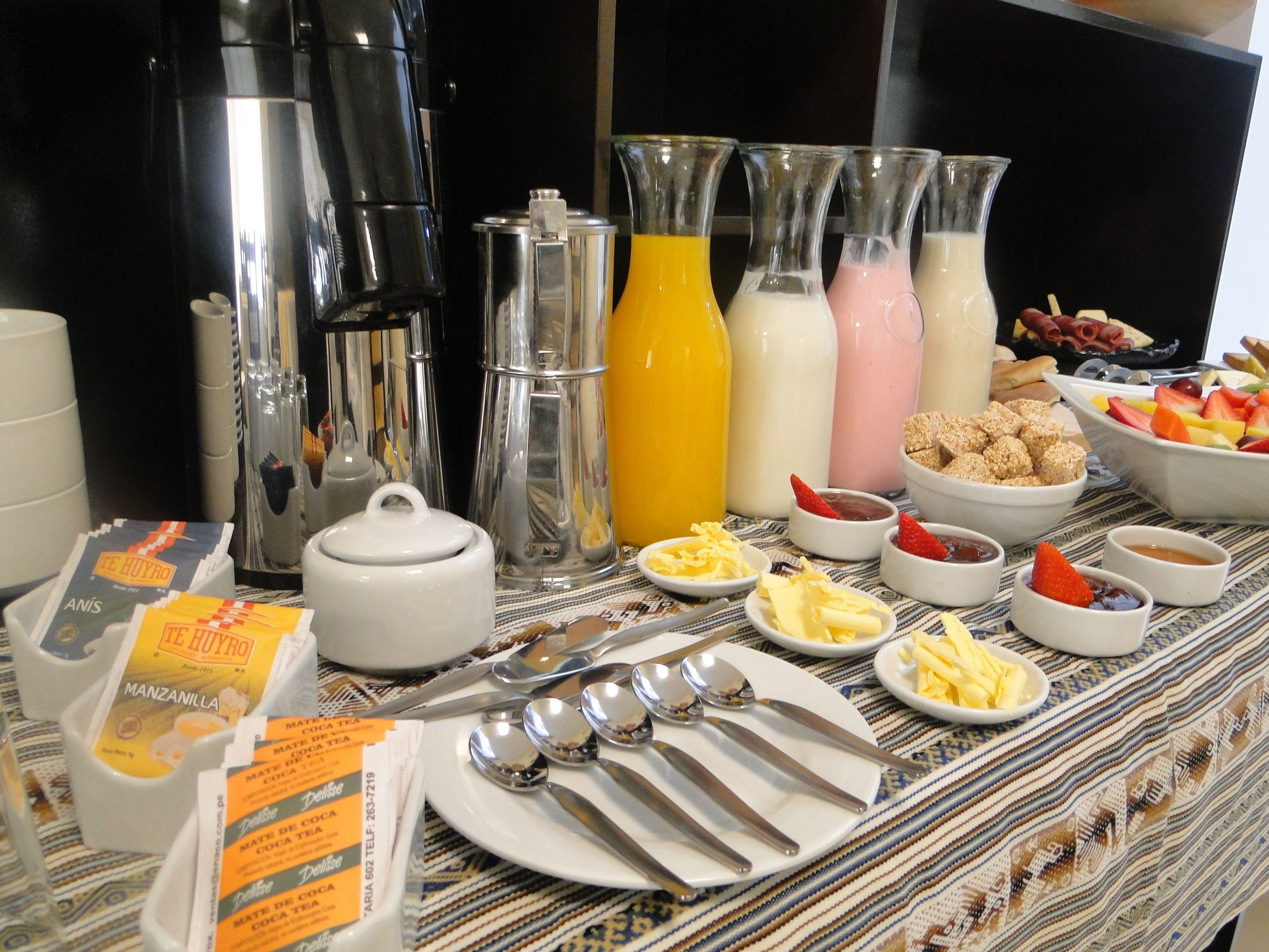 A breakfast buffet with various beverages, fruits, and pastries.