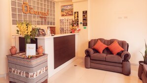 A reception area with a reception desk, a sofa, and a decorative vase. - Hotel Las Quenas (Cusco)