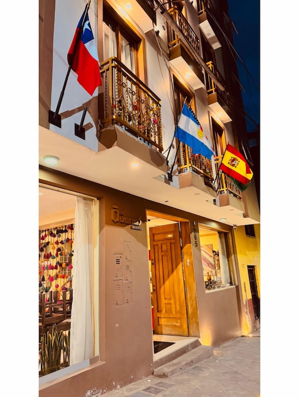 A hotel facade with balconies, a visible entrance, and flags. - Hotel Las Quenas (Cusco)