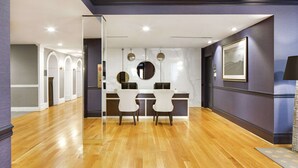 A modern dining area with a marble countertop, two chairs, and pendant lighting.