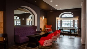 A modern interior with a purple sofa, red chairs, a wooden table, and a patterned bench.