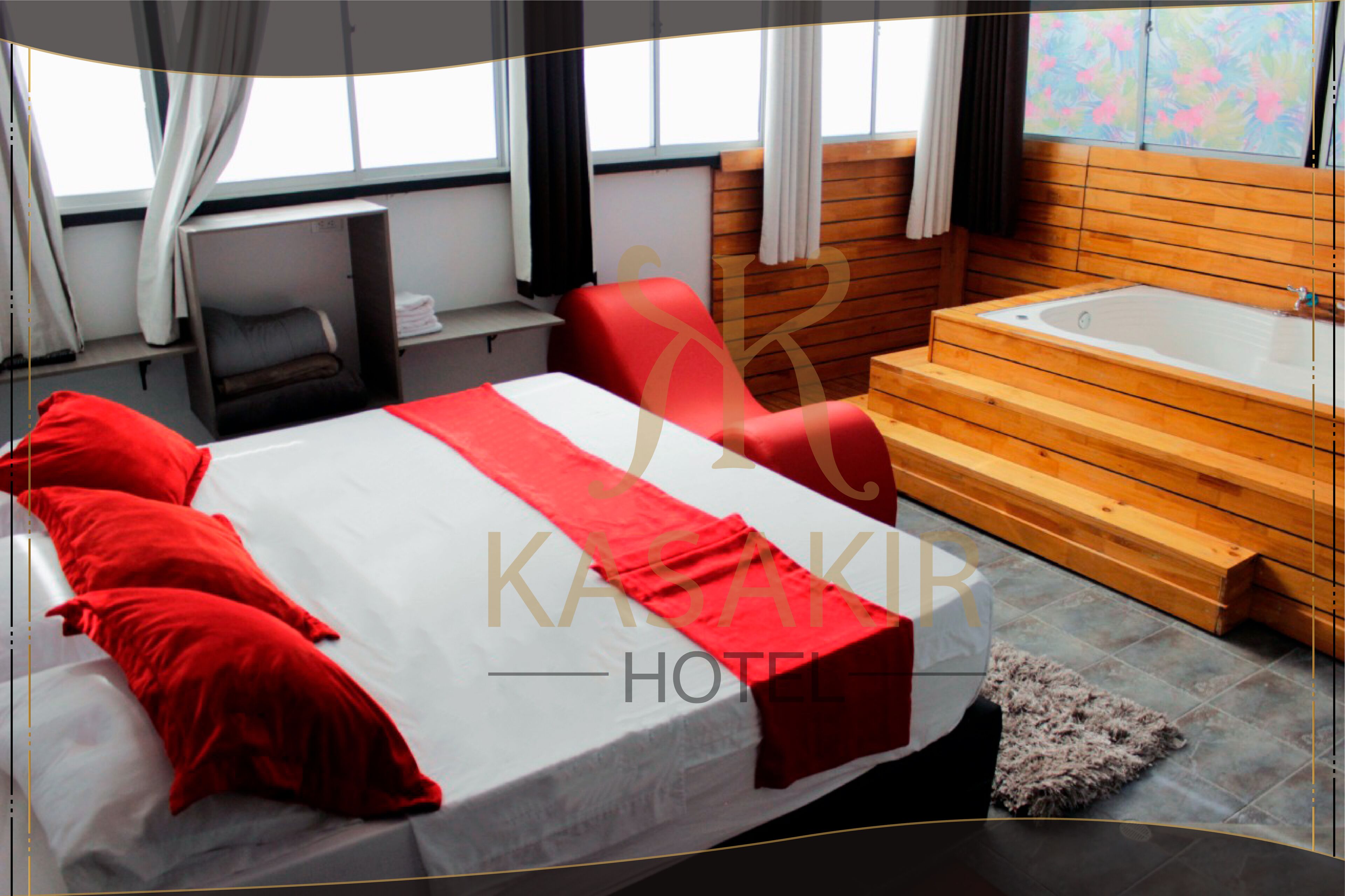 Ein Hotelzimmer mit einem Bett, einem roten Sessel, einer hölzernen Bank und einer Badewanne.