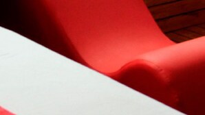 Una habitación con una cama, una silla roja y un panel de madera en la pared.