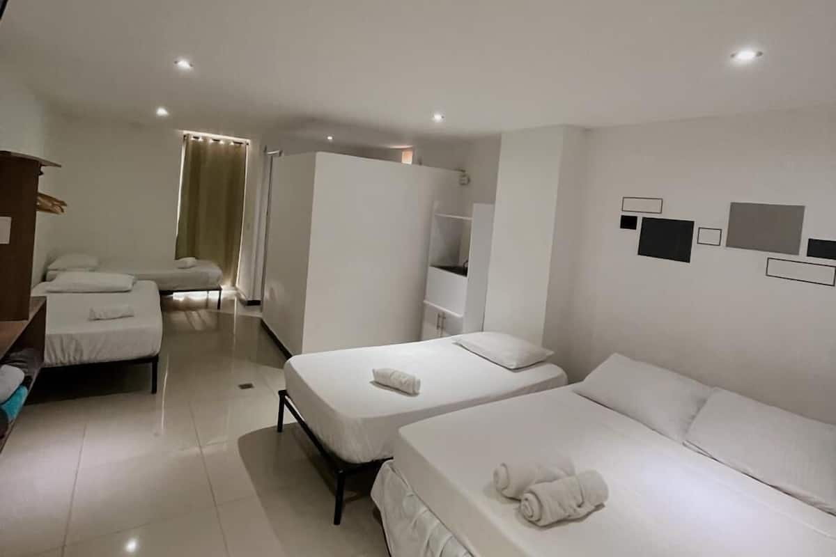 A hotel room with two single beds, a small desk, a wardrobe, and a bathroom with a shower.