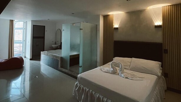 Una habitación de hotel moderna con una cama grande, baño independiente y vistas al exterior.