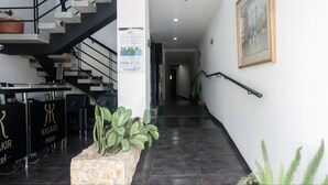 Un vestíbulo de hotel con una escalera, una recepción y plantas en macetas.