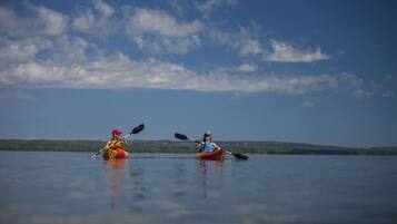 Two kayakers in a calm lake with a clear sky.