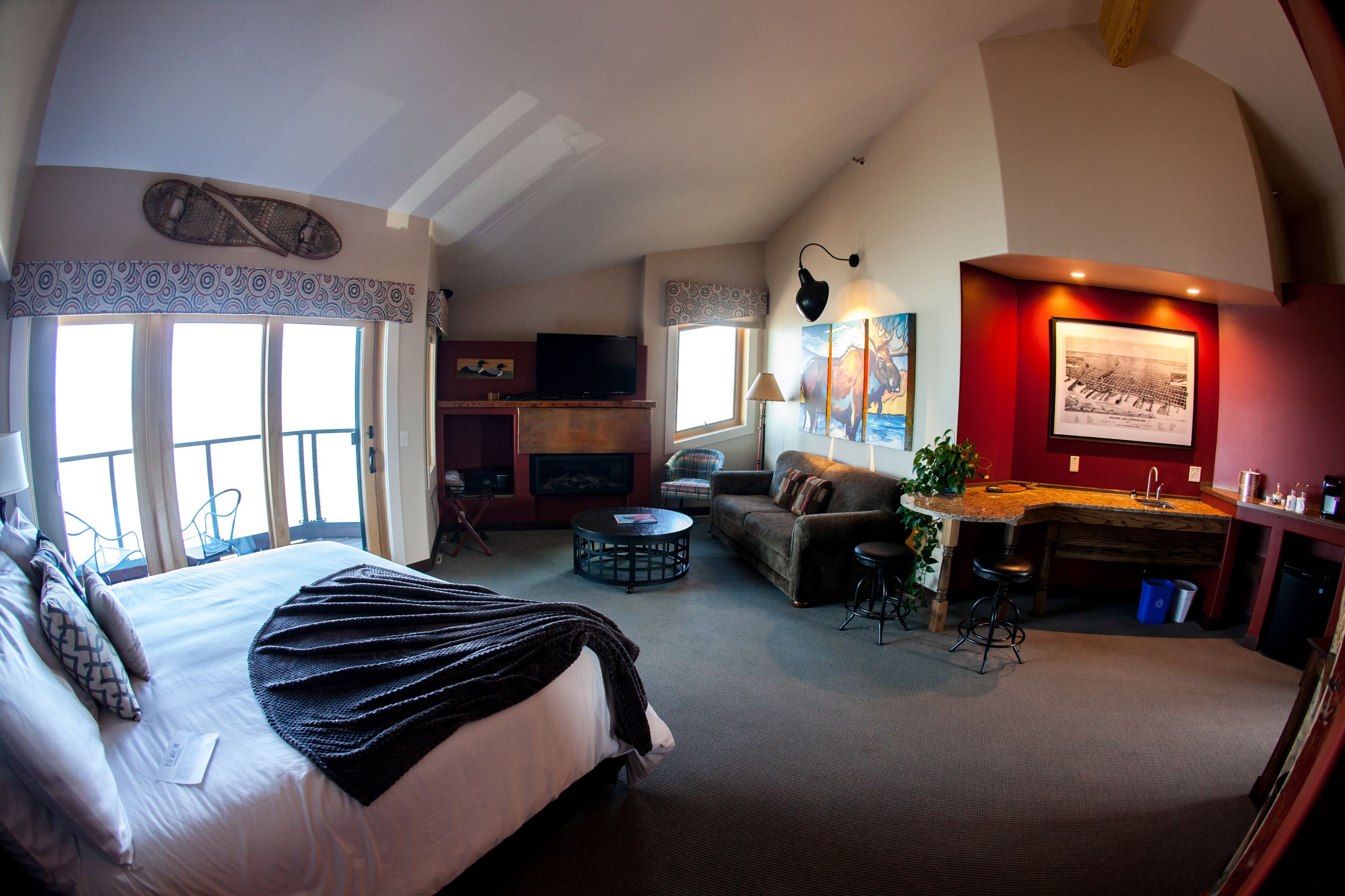 A spacious room with a large bed, a sofa, a dining area, and a fireplace.