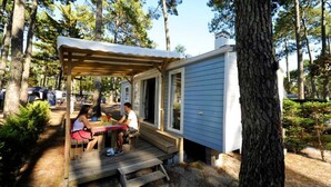 Uma cabana pequena com um deck de madeira e uma área de estar coberta.