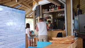 Um café rústico com decoração de madeira, um balcão com pão e um quadro de ementa.
