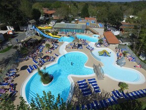 A large outdoor swimming pool with multiple lanes, sun loungers, and a water slide.