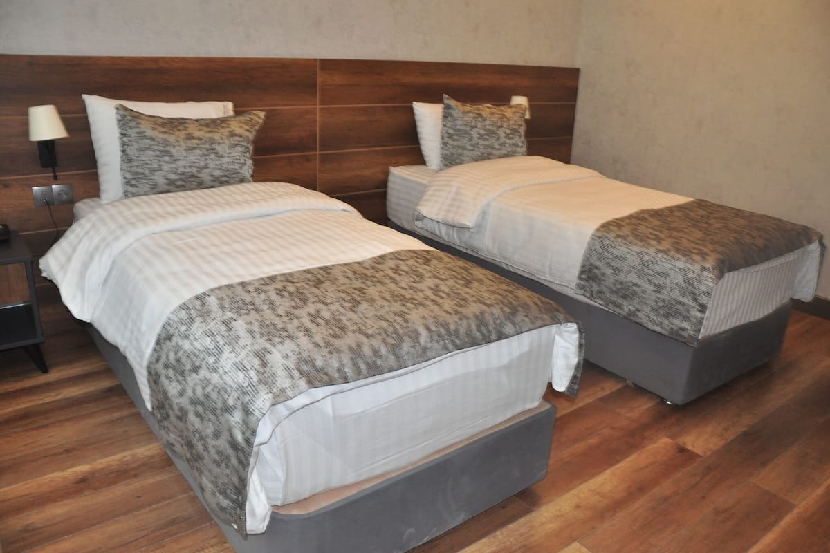 A double bed with a wooden headboard, a bedside table, and a wall-mounted lamp.