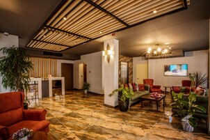 Una hall con reception, area salotto e schermo televisivo.