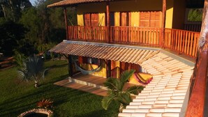 A two-story building with a wooden balcony and a hammock. - Pousada Estancia do Vale (Jaboticatubas)