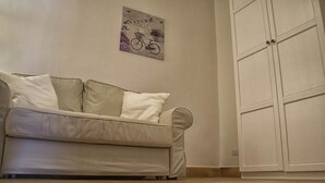 A beige sofa with pillows against a wall, a framed picture above it, and a white wardrobe to the right. - Le sette perle (Malfa)