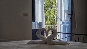 A bedroom with a bed, a window with curtains, and a view of greenery outside. - Le sette perle (Malfa)