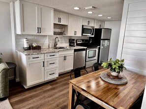 Une cuisine moderne avec des meubles blancs, des appareils en acier inoxydable et une table à manger en bois.
